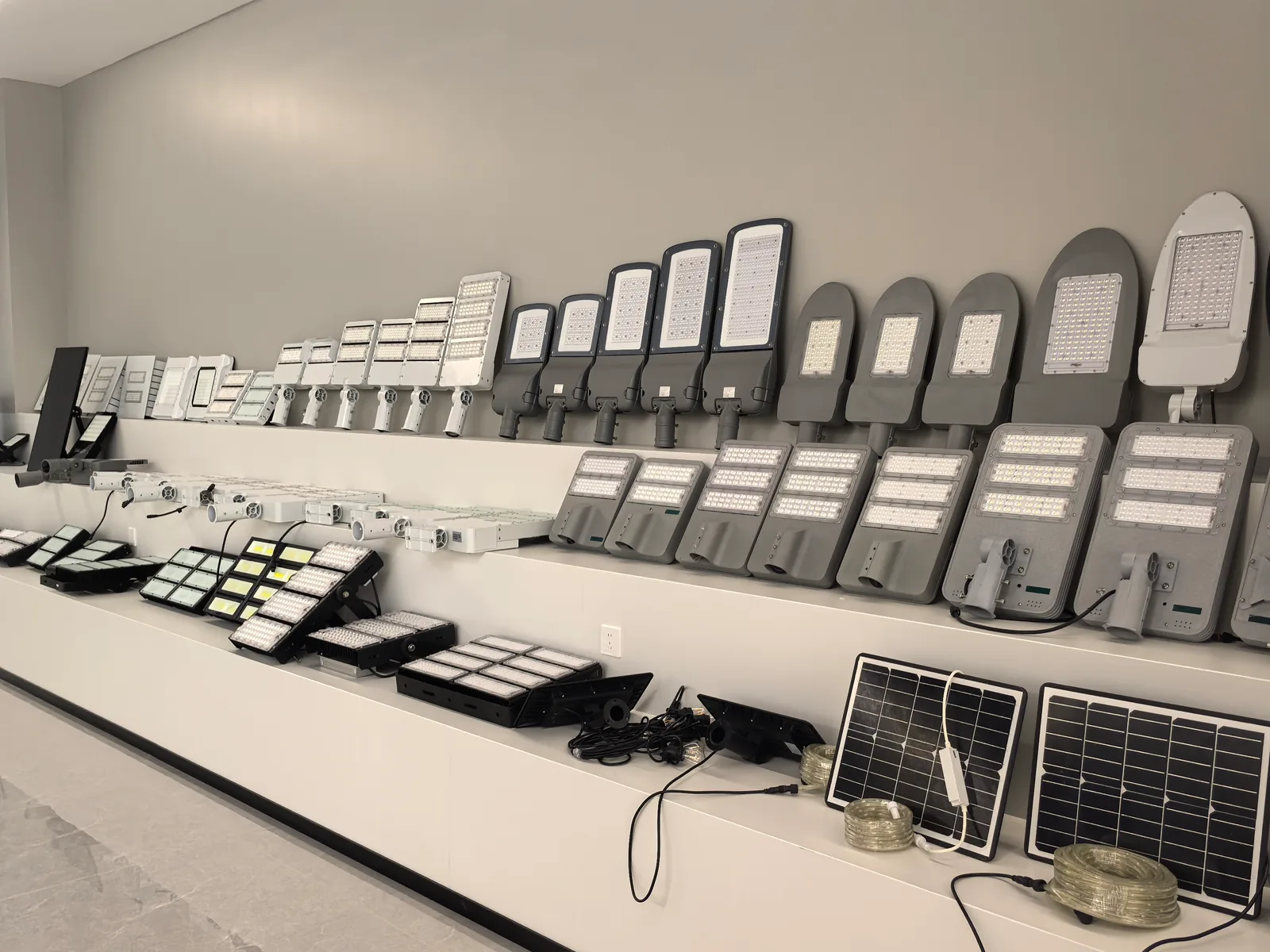 Showroom shelving displaying solar street light heads ordered by wattage alongside solar panels